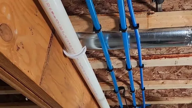 Blue PEX water lines clipped beside a white PVC pipe and a metal duct between wood floor joists