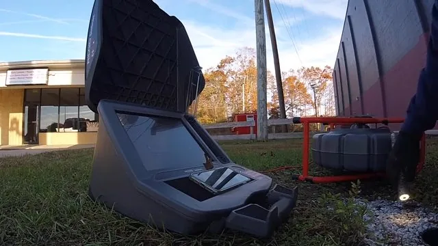 Sewer camera monitor case and reel set out on grass beside a building