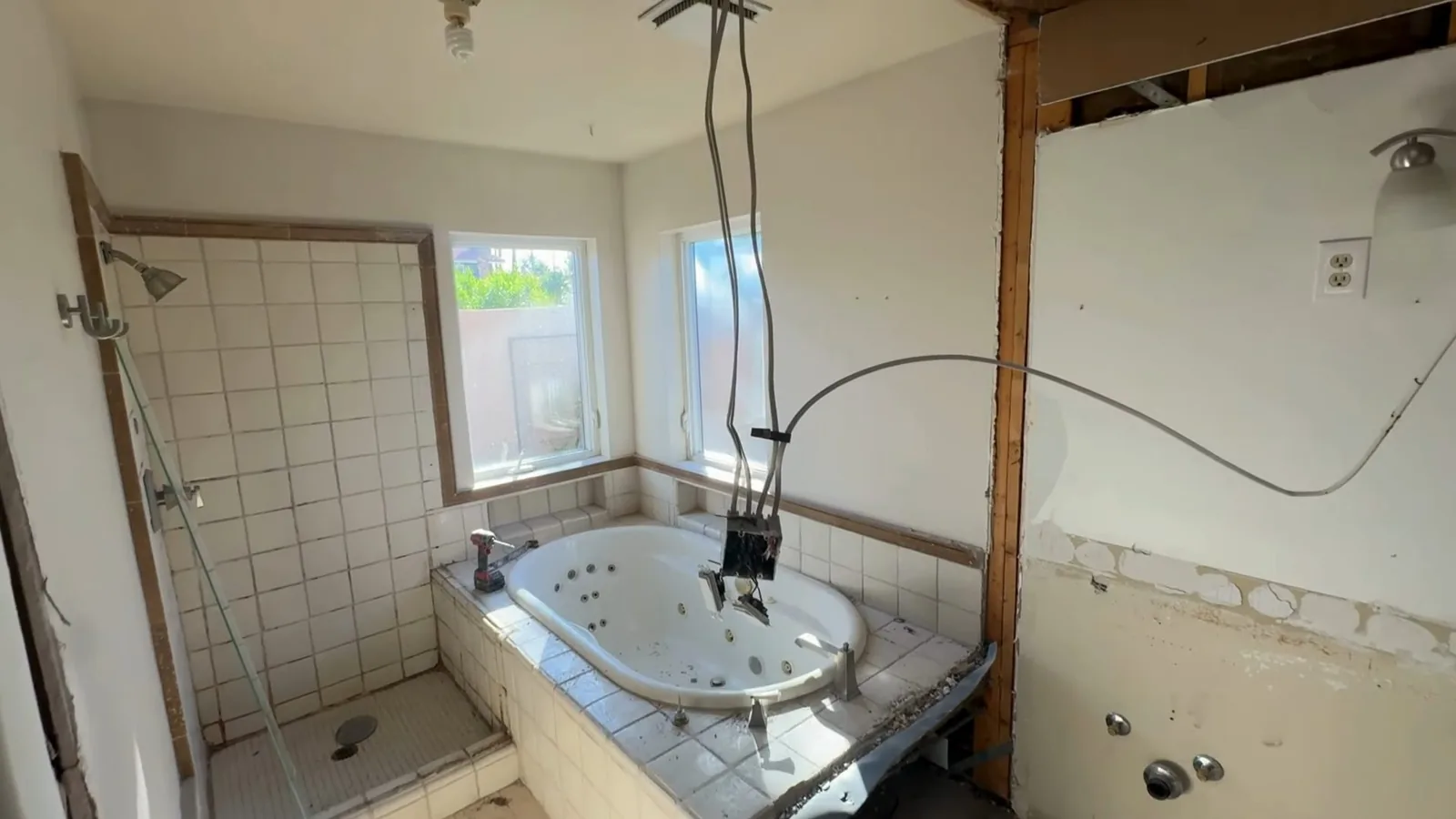 Bathroom stripped to the studs with a tiled shower stall and a tub deck still in place