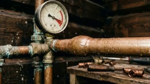 Pressure gauge on a copper pipe manifold with water droplets on the pipes