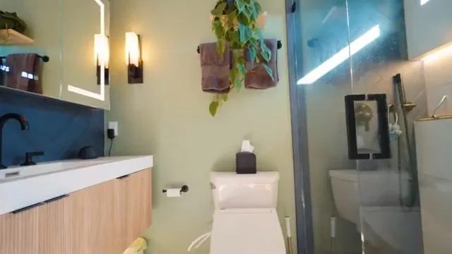 Small renovated bathroom with a wood vanity, glass shower and a wall toilet